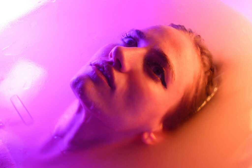 pexels-photo-20405789-20405789 Surreal portrait of a woman submerged in water with vibrant purple lighting.